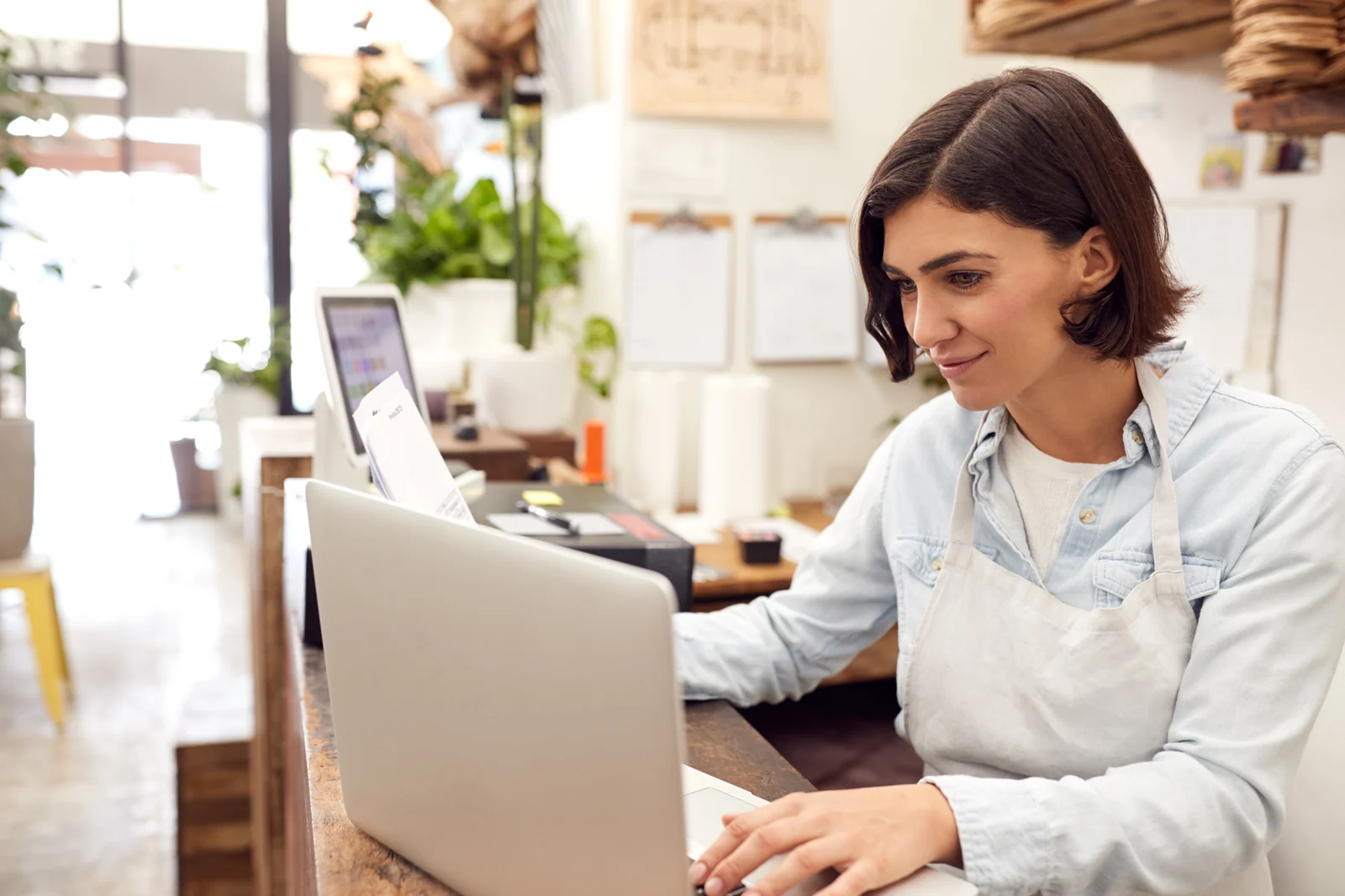 Blomsterhandler ved disken med laptop i en lys butikk